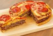 Homemade pizza burger pie with a crispy golden crust, gooey melted cheese, seasoned ground beef, and colorful pizza toppings, perfect for a hearty and flavorful meal