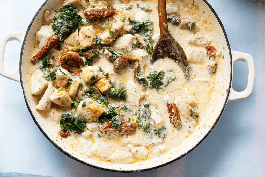 Marry Me Chicken Recipe: Make Marry Me Chicken Pasta—A Chicken Pasta So Good, You’ll Want to Propose on the Spot! 11 A bright, close-up image featuring tender chicken chunks nestled in a creamy, garlic-infused sauce. The spinach and sun-dried tomatoes add pops of color, illustrating the dish’s indulgent texture and hearty appeal.